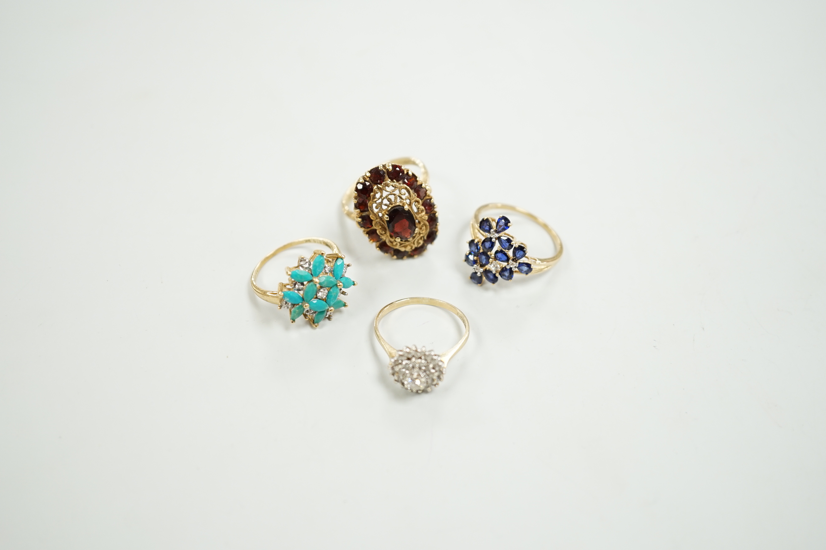Four assorted modern 9ct gold and gem set dress rings including diamond cluster and garnet cluster, gross weight 13.6 grams.